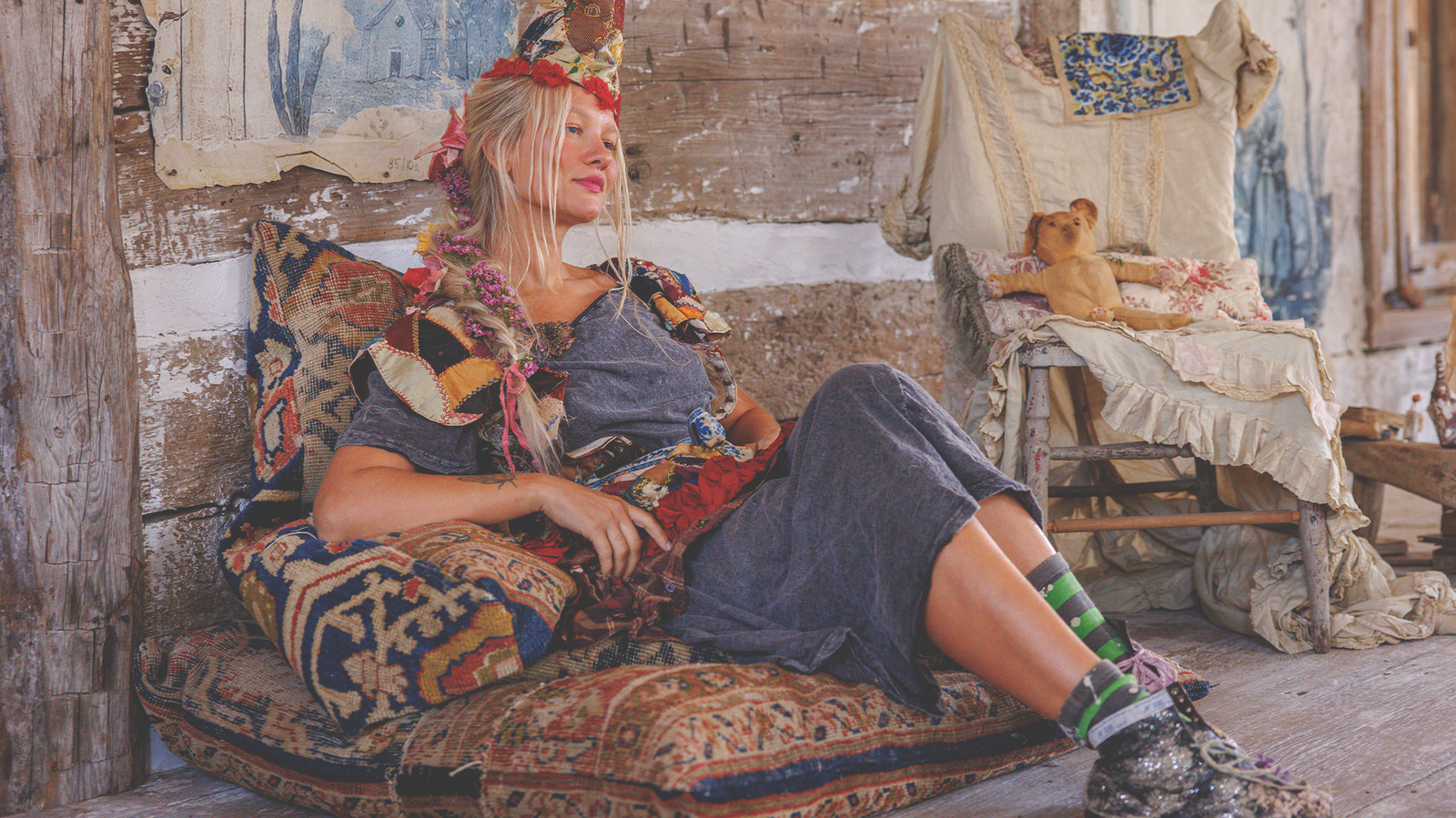 Woman in Magnolia Pearl artisan clothing with whimsical, vintage style lounging on boho pillows