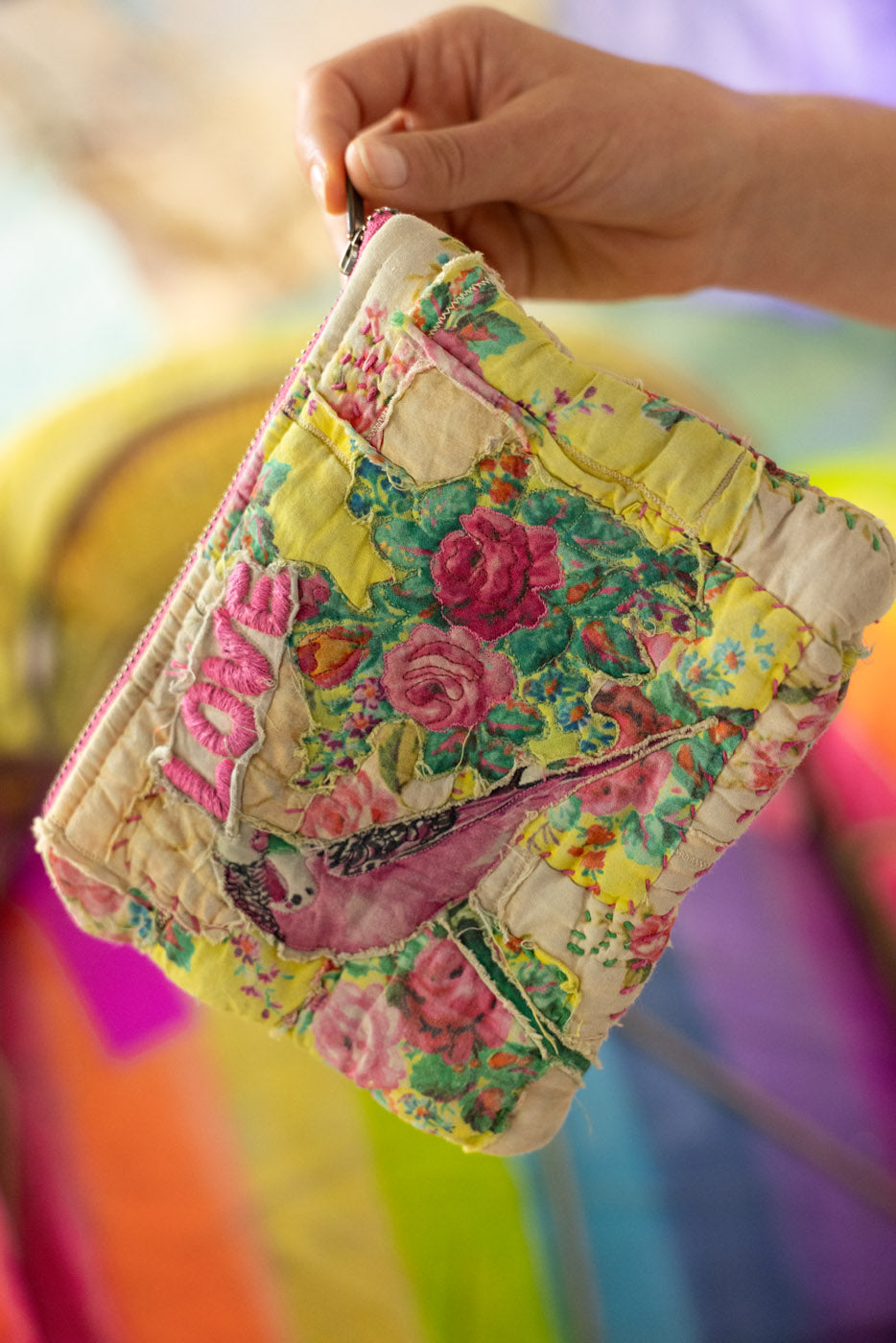 Colorful floral-patterned fabric zipper bag and or makeup bag  held by a hand against a blurred background