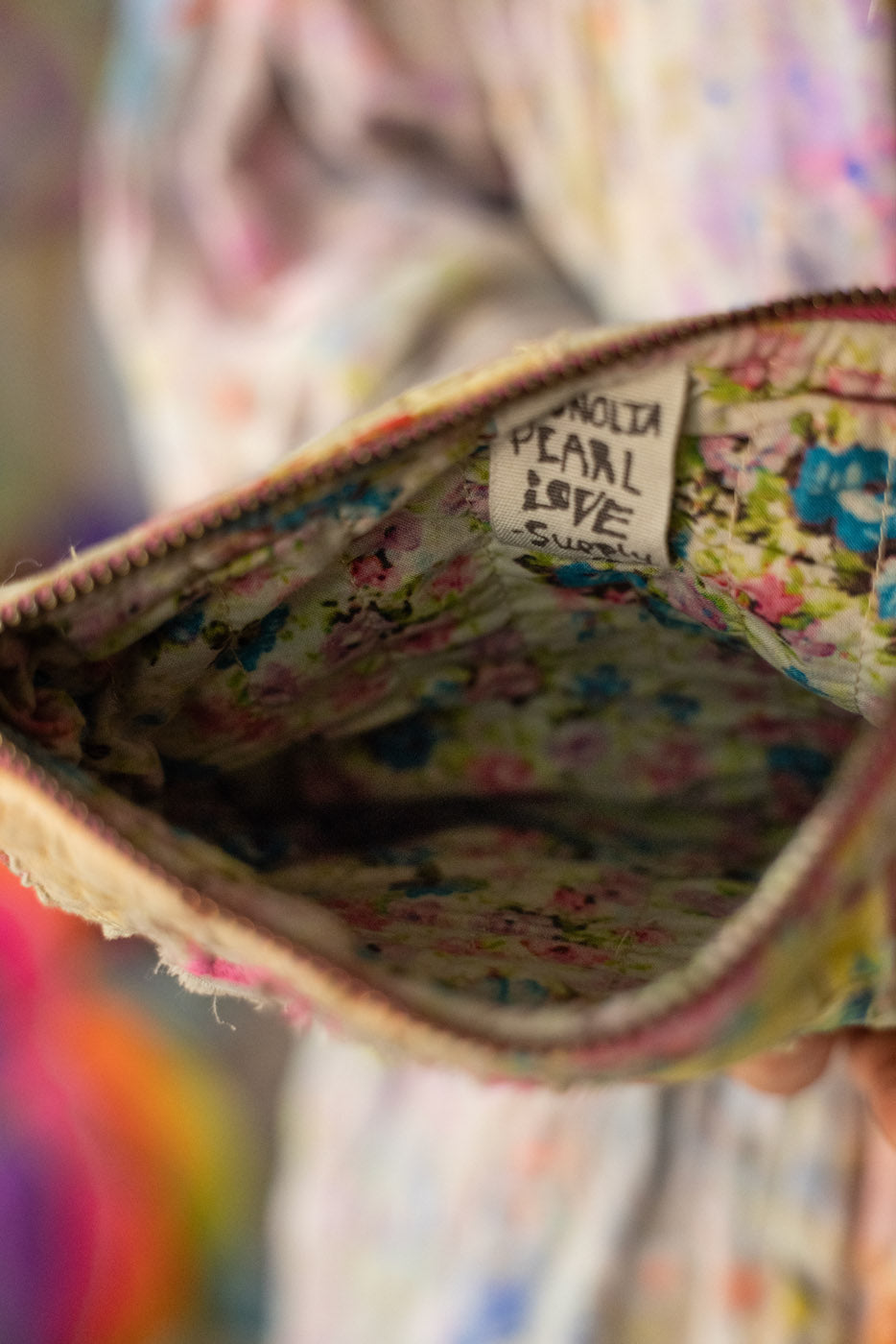 Floral fabric zipper pouch makeup bag small bag with a visible magnolia pearl love supply co. brand label inside a colorful bag.