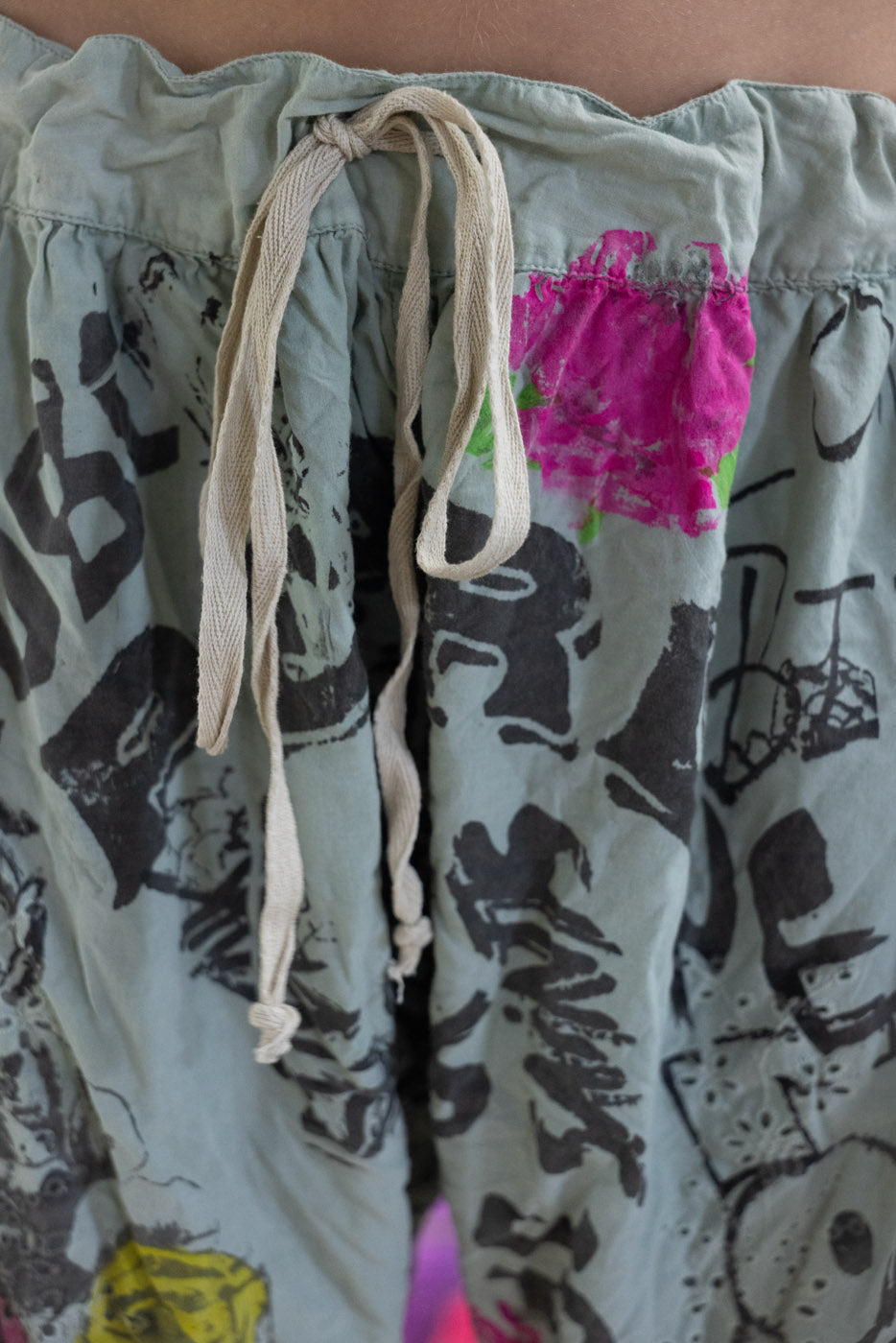 Light green shorts with black abstract patterns and pink floral design on a blurred background