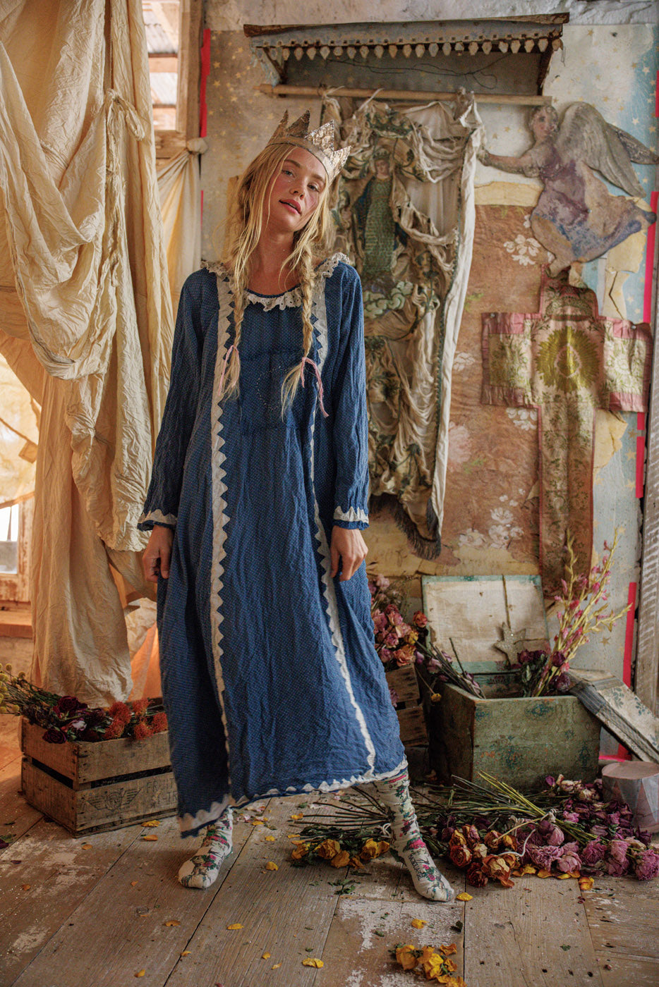 Woman in Magnolia Pearl artisan blue vintage dress with crown, whimsical floral rustic setting