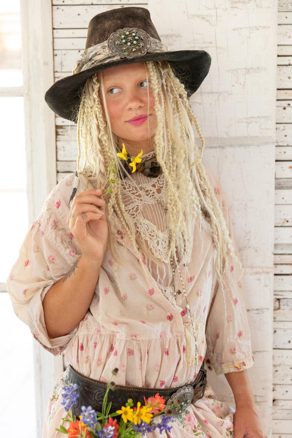 Woman in Magnolia Pearl artisan vintage dress and hat holding wildflowers, whimsical boho style