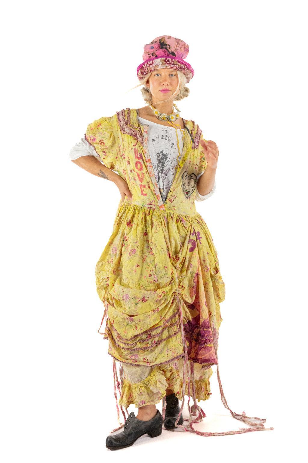 Woman in Magnolia Pearl artisan vintage yellow dress, whimsical pink hat, unique boho style