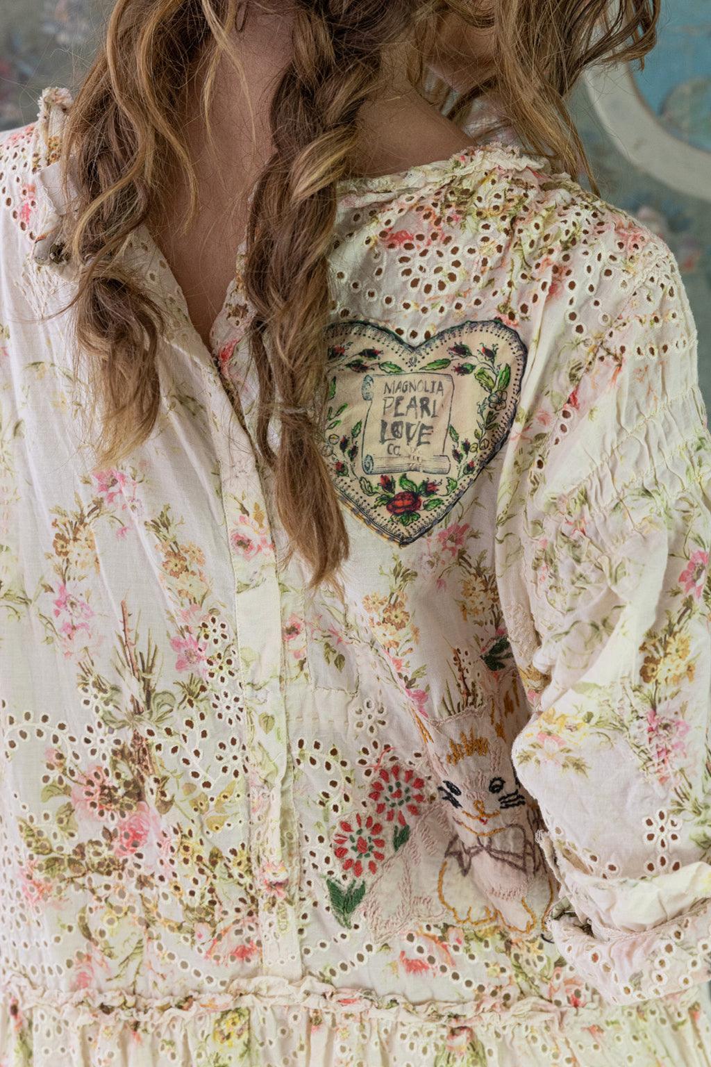 Woman in Magnolia Pearl artisan vintage floral dress, lace hat, whimsical pink socks, rustic setting