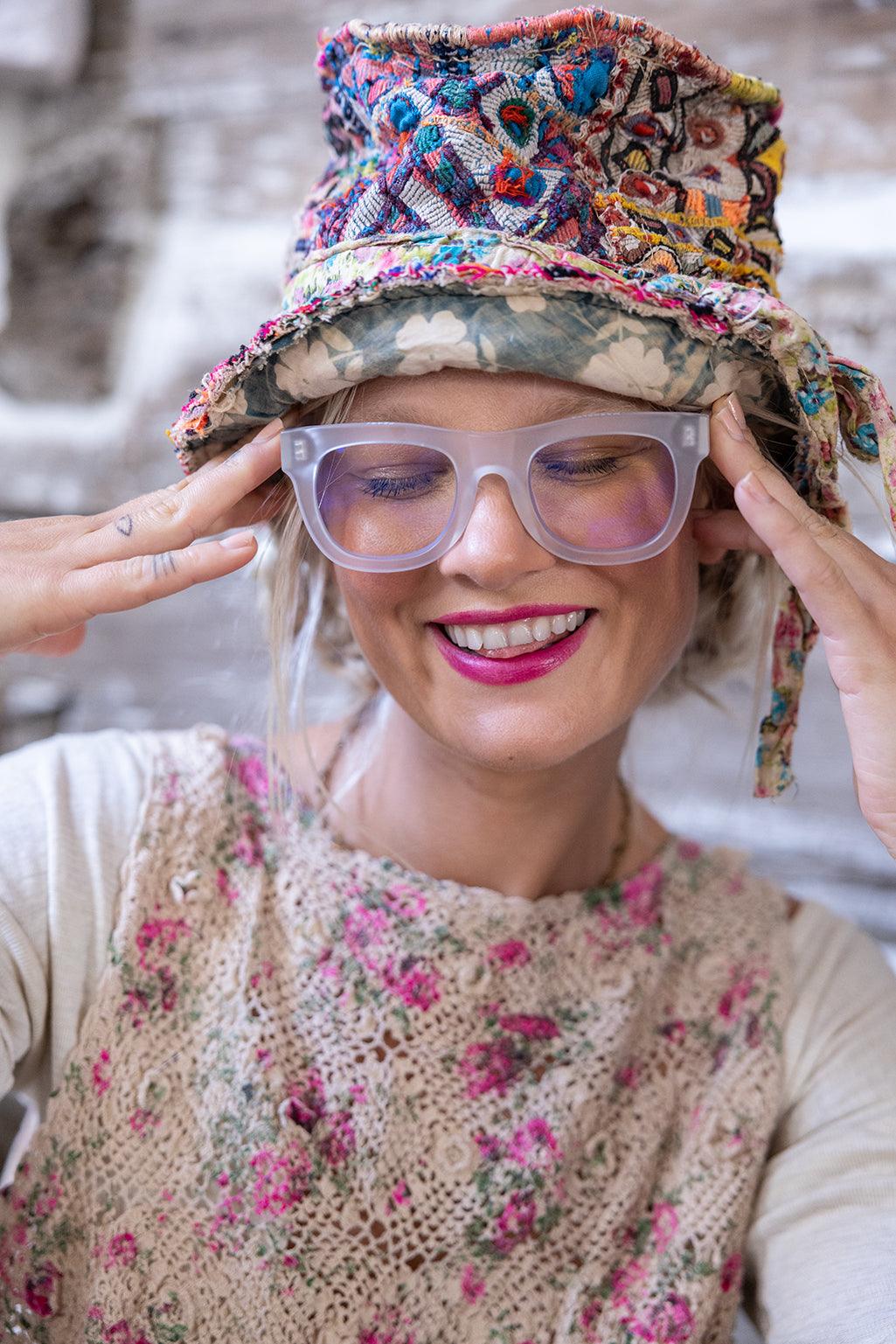 Smiling woman in Magnolia Pearl artisan floral crochet top and whimsical embroidered vintage hat