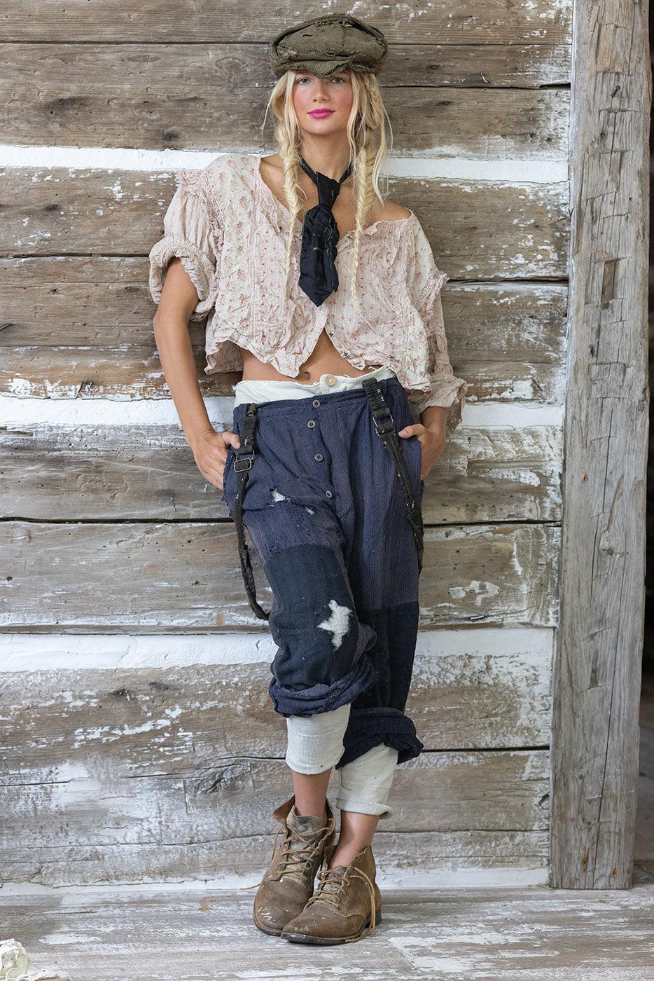 Woman in Magnolia Pearl artisan vintage clothing with whimsical design, standing in rustic room by antique statues