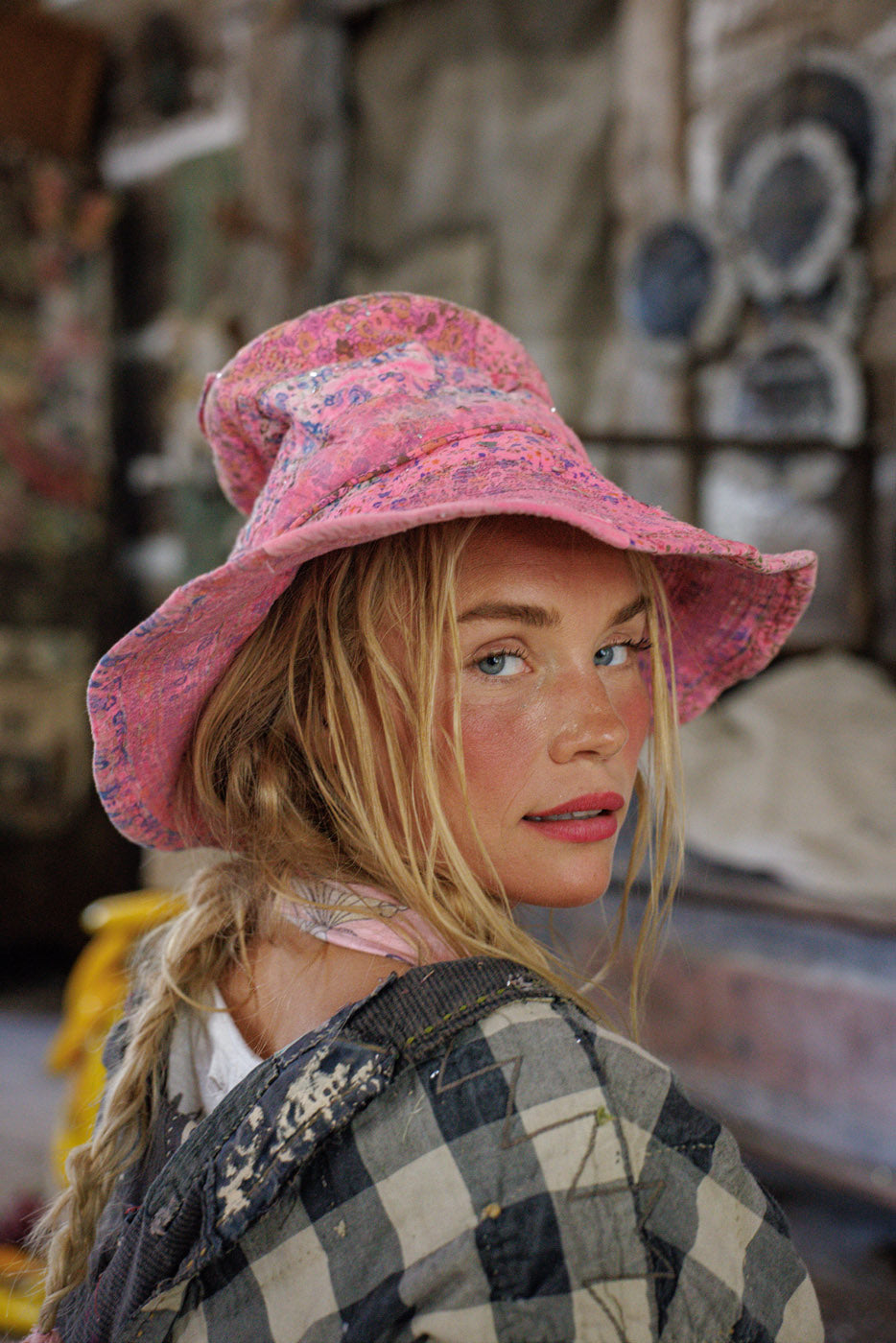 Woman in Magnolia Pearl vintage artisan pink floral hat and patchwork jacket, whimsical style