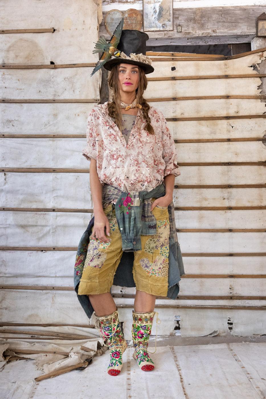 Woman in Magnolia Pearl artisan clothing with whimsical patched shorts, floral boots, vintage hat