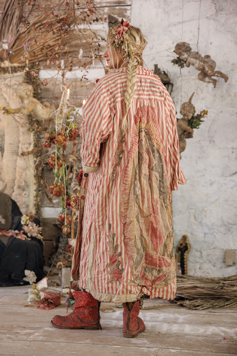 Woman in Magnolia Pearl artisan red striped vintage jacket with floral patches and sparkly boots in whimsical rustic setting