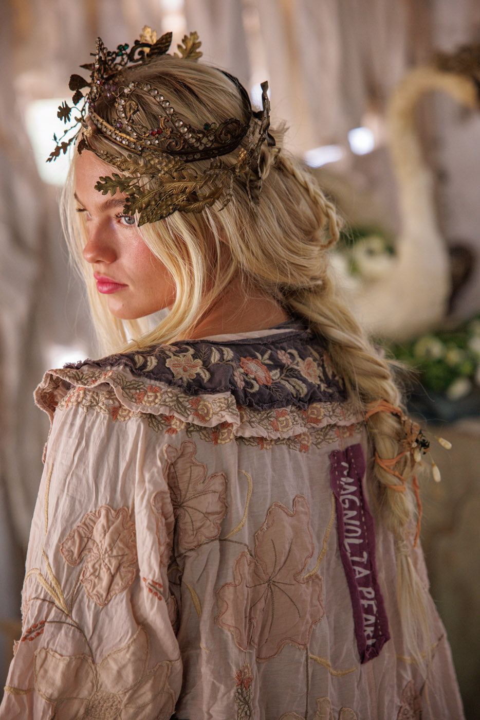 Woman in Magnolia Pearl artisan jacket with floral embroidery and ornate crown, vintage whimsical style
