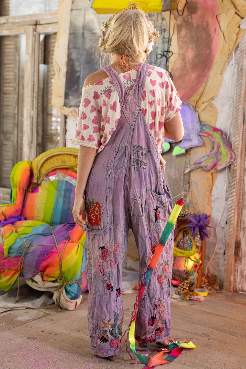 Person wearing a colorful overalls outfit with a vibrant background.