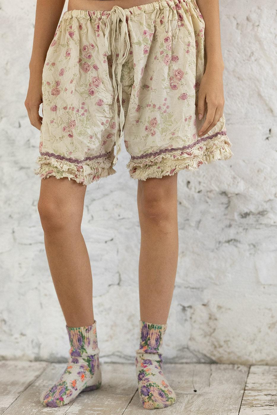 Magnolia Pearl artisan floral shorts with ruffle trim and whimsical vintage style, modeled indoors