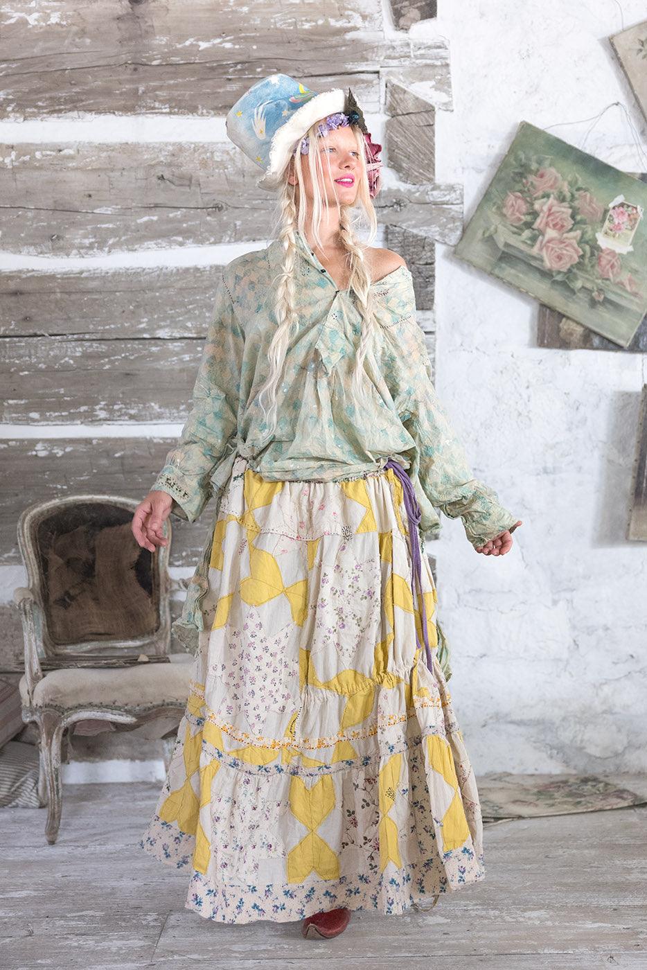 Woman in Magnolia Pearl artisan vintage skirt, whimsical hat, holding floral book, rustic decor