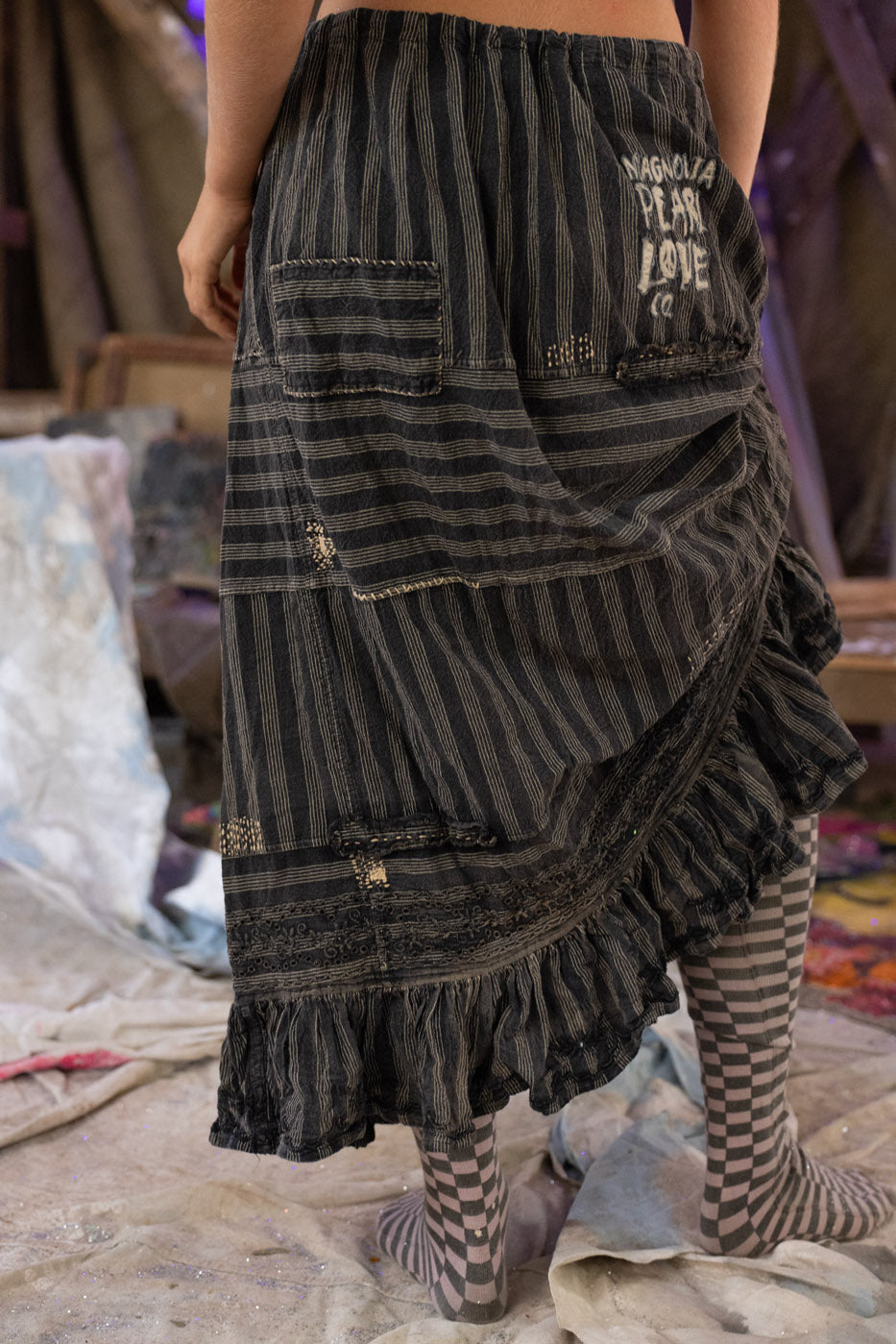 Person wearing a black and gray striped skirt with layered ruffles in an indoor setting.