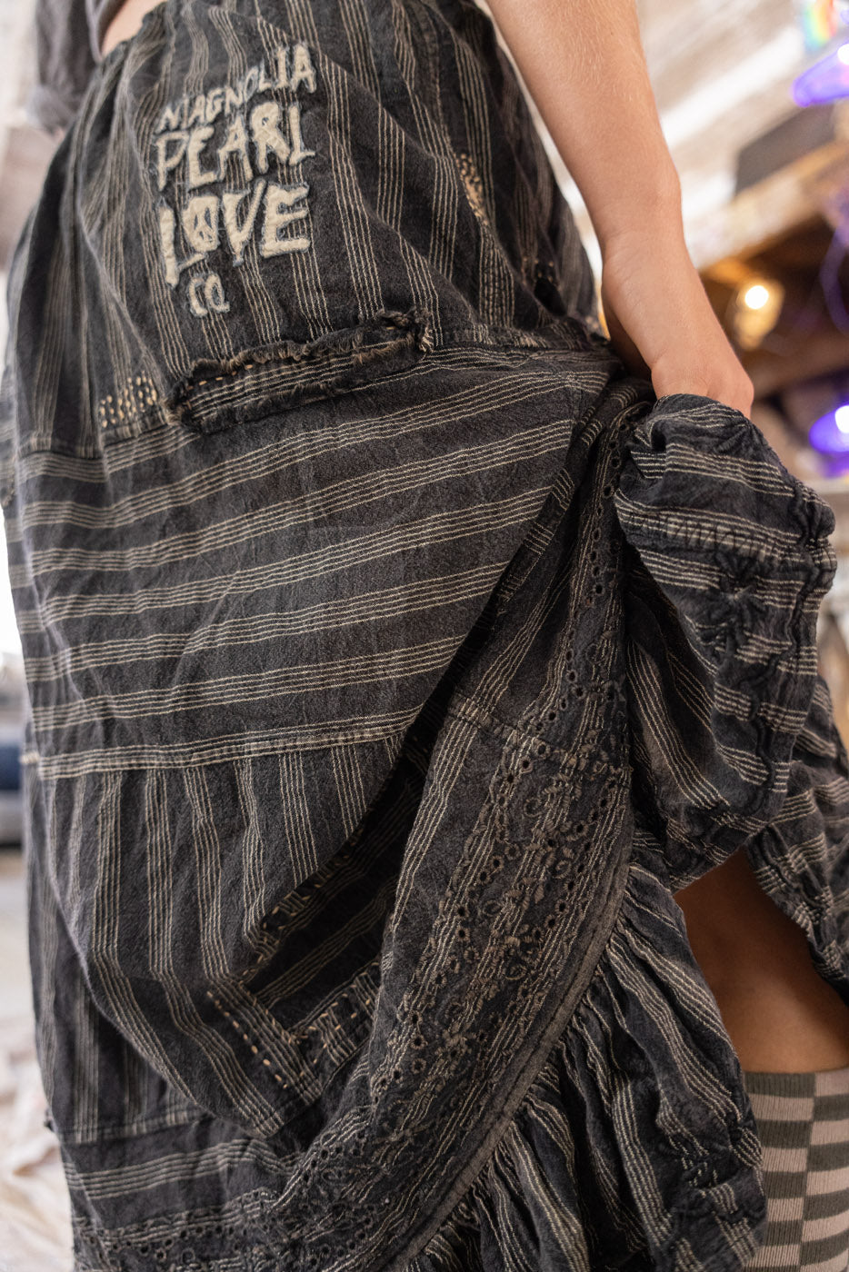 Person wearing a long, gray skirt eith ruffles showing checkered socks.