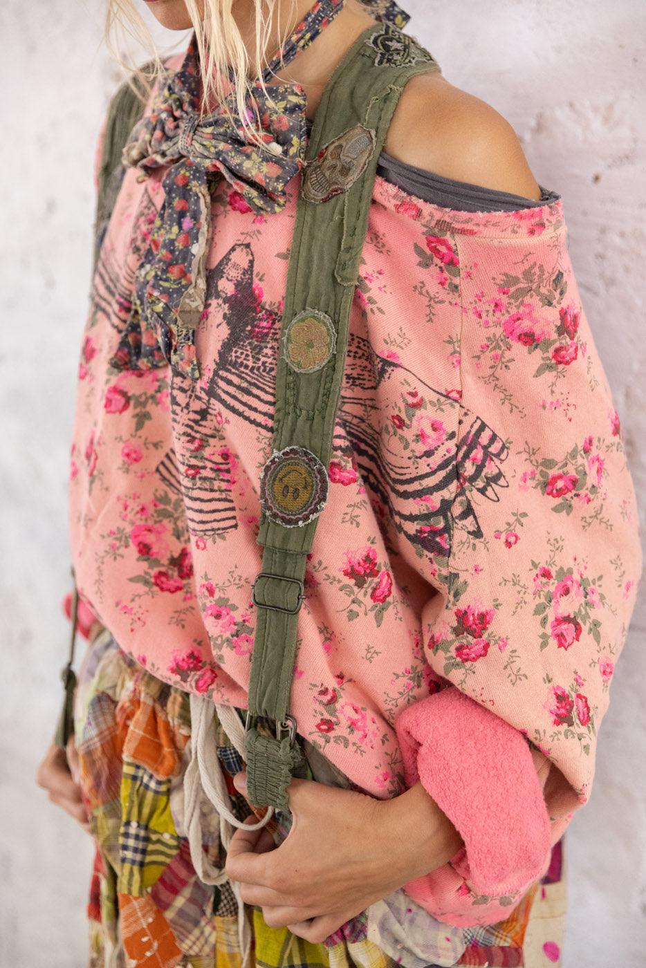 Magnolia Pearl artisan clothing model in floral pink sweater, patchwork skirt, vintage suspenders, and wide hat