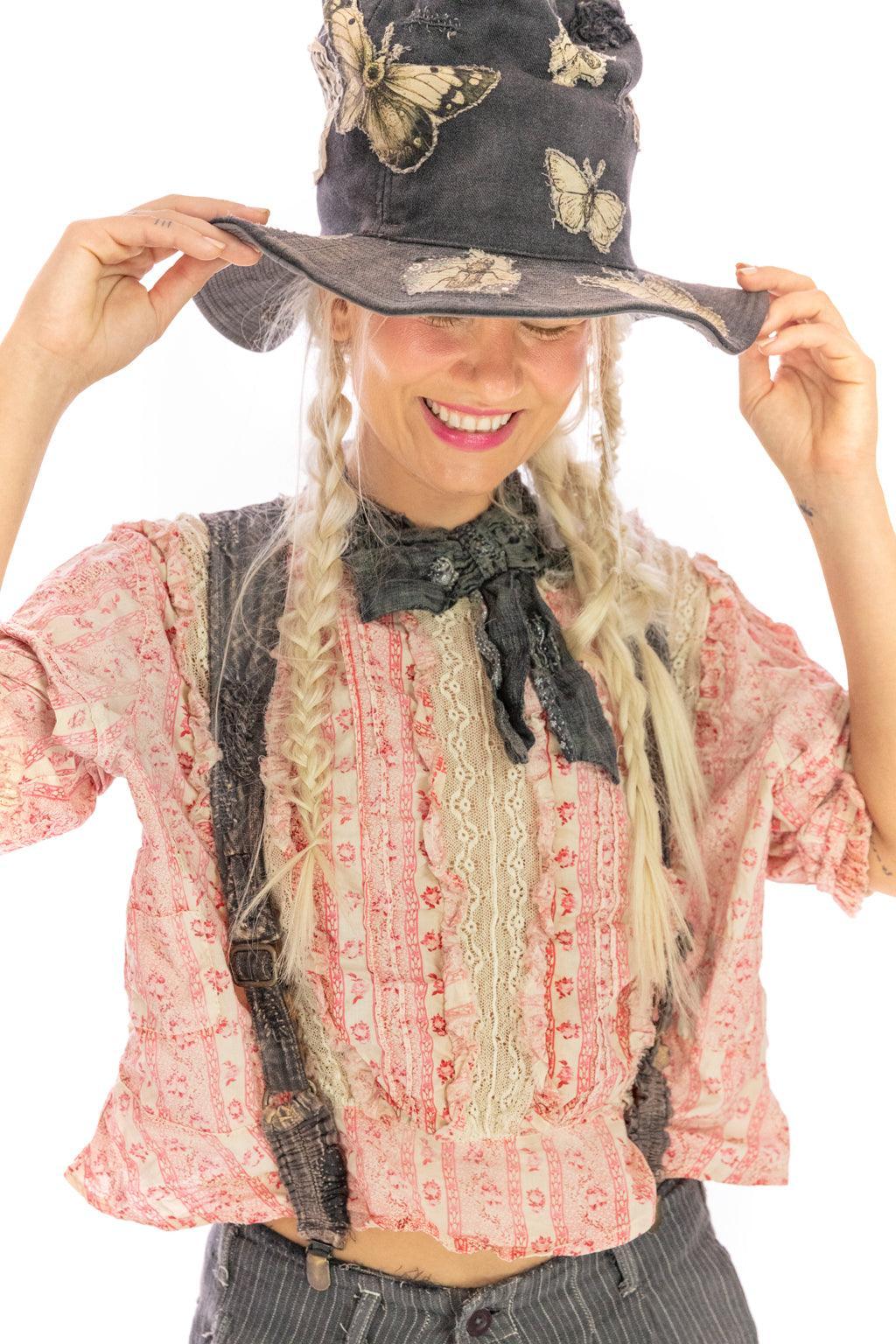 Woman in Magnolia Pearl artisan vintage pink floral lace blouse, suspenders, butterfly hat, whimsical style