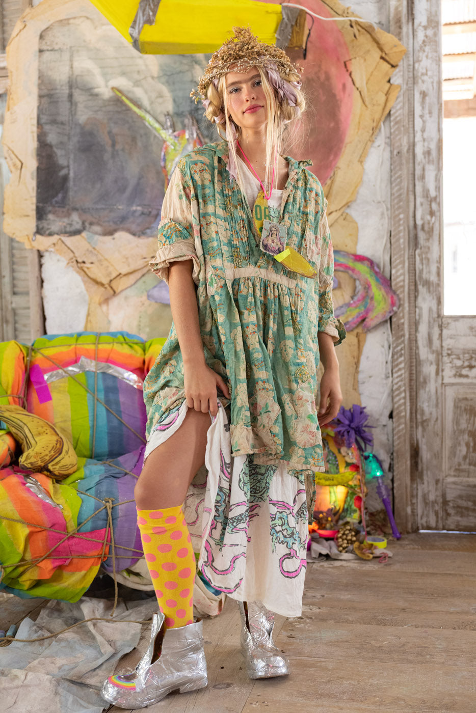 Woman in a colorful outfit standing in a vibrant, artistic indoor setting.