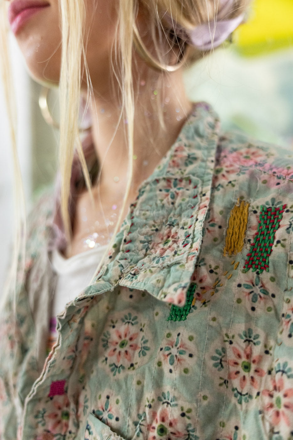 Close-up of a person wearing a floral patterned blouse with a blurred background