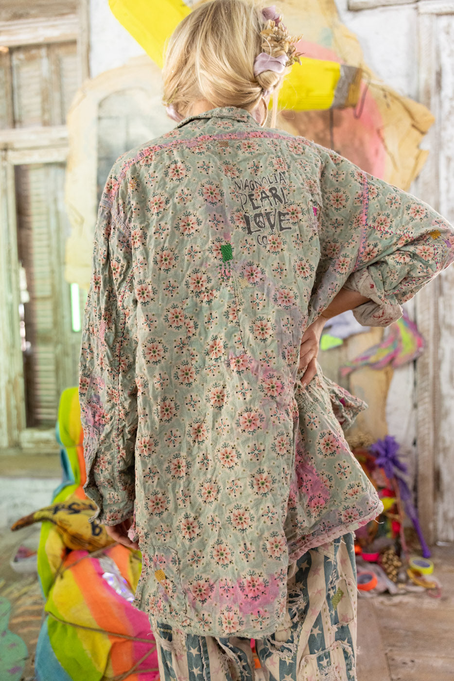 Person wearing a floral button down blouse with colorful background