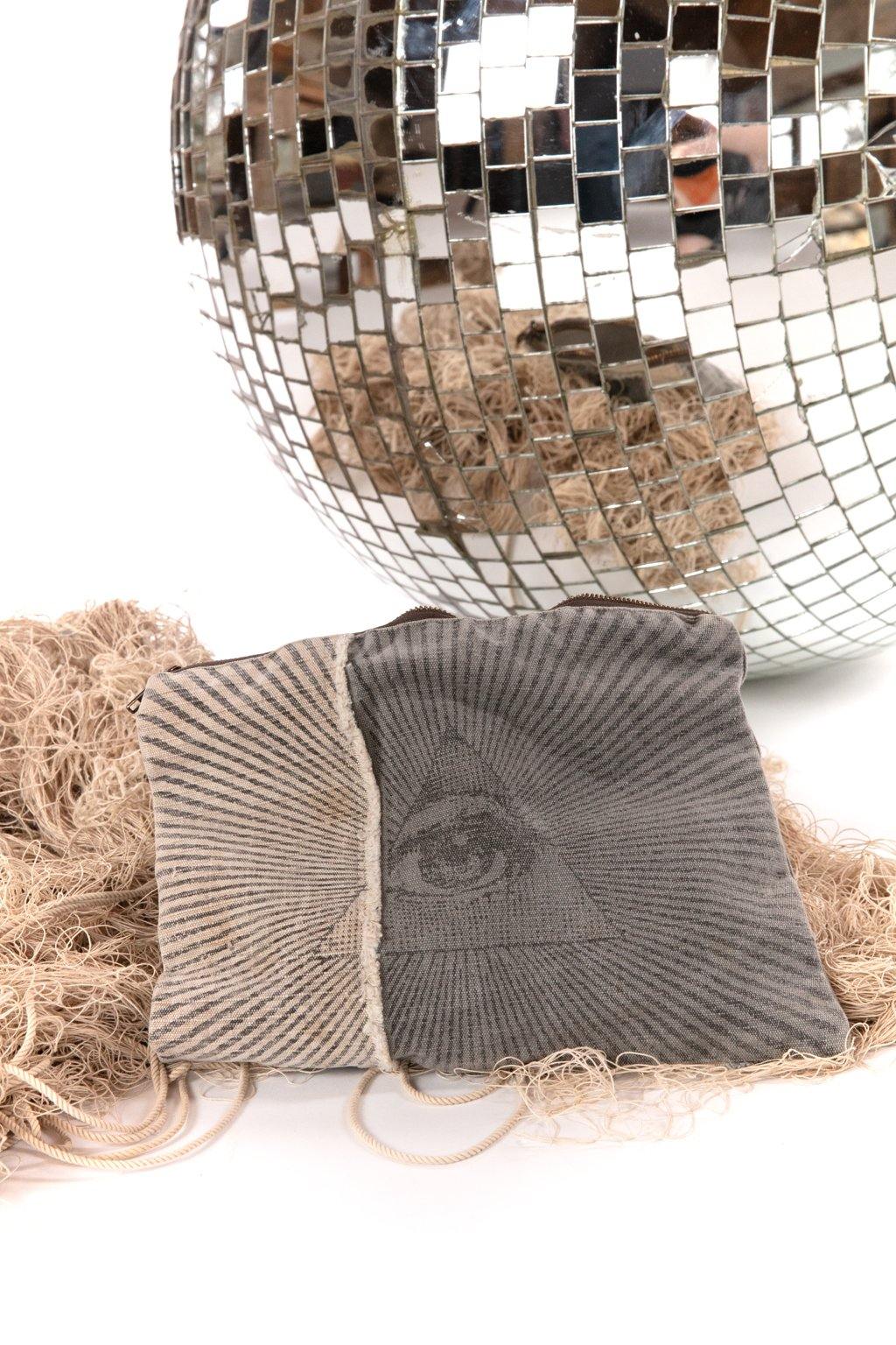 Gray zippered pouch with all-seeing eye design in front of a mirrored disco ball