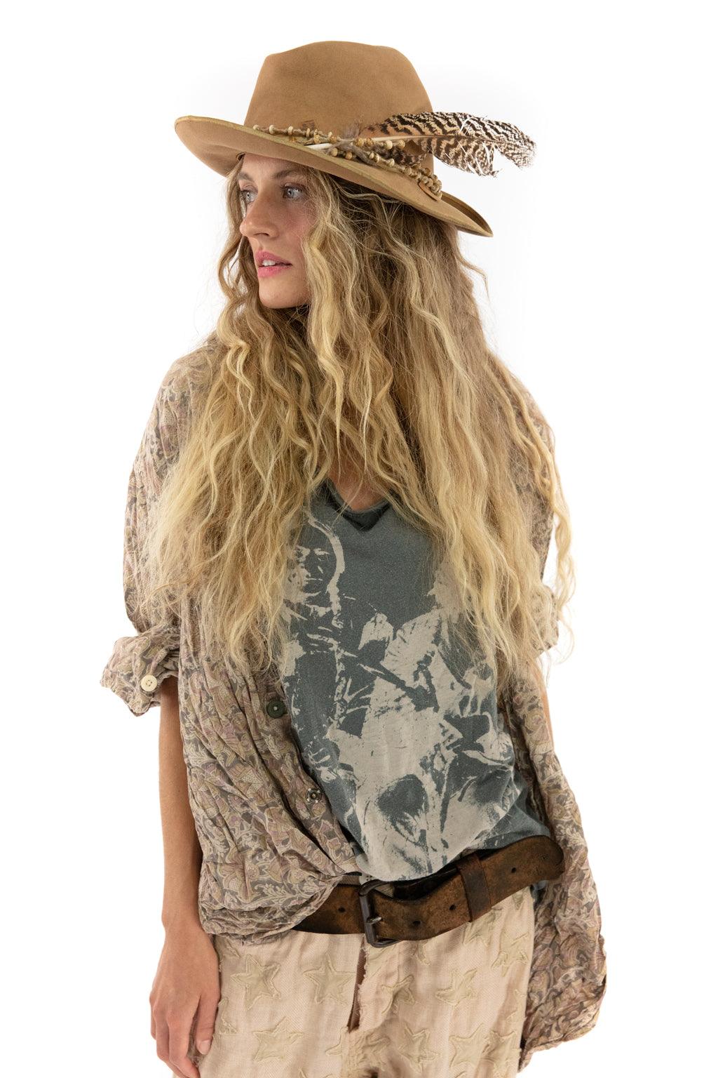 Woman in Magnolia Pearl artisan vintage blouse, graphic tee, and feather hat, whimsical boho style