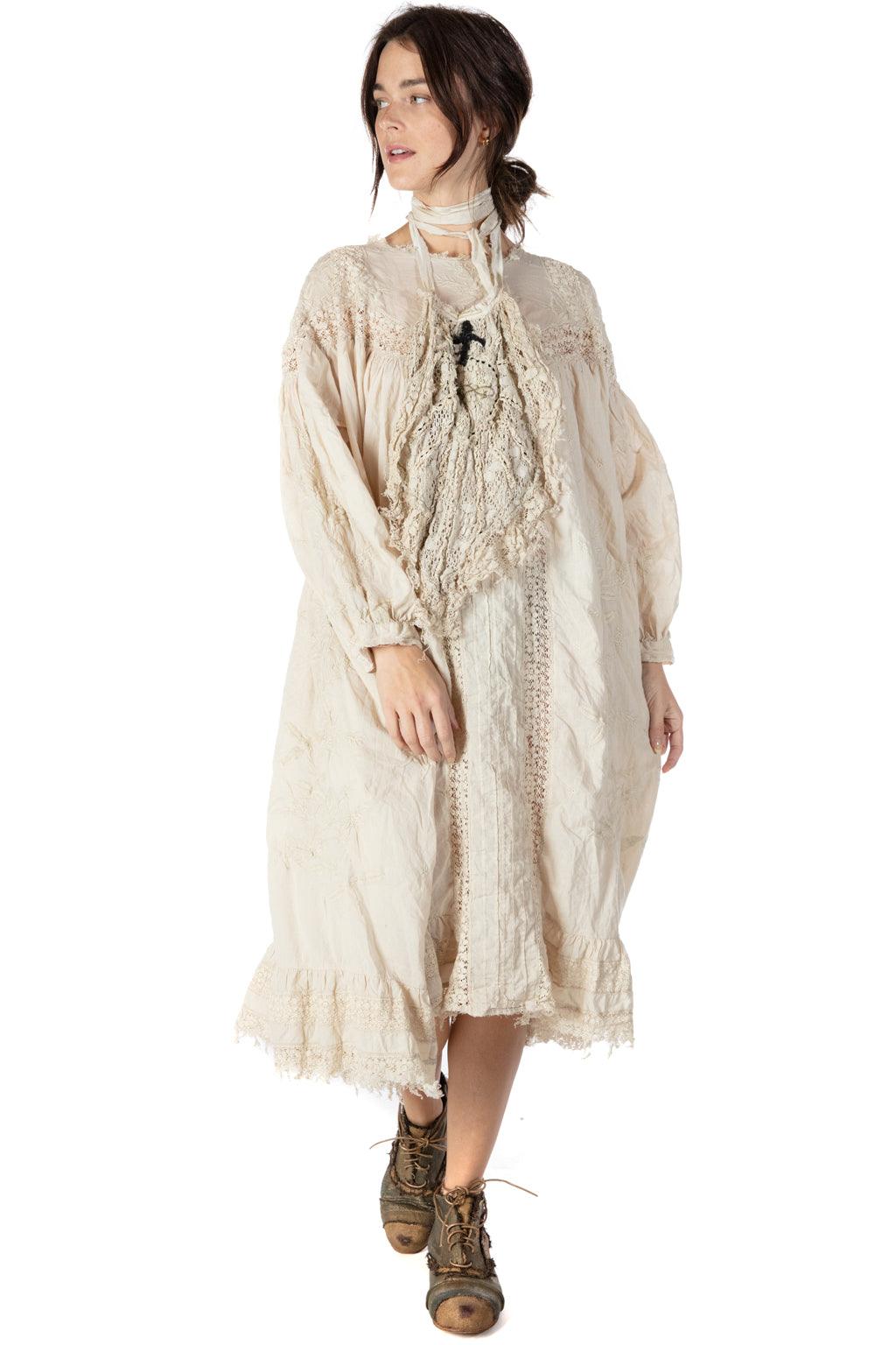Woman wearing loose vintage cream lace dress and ankle boots on white background