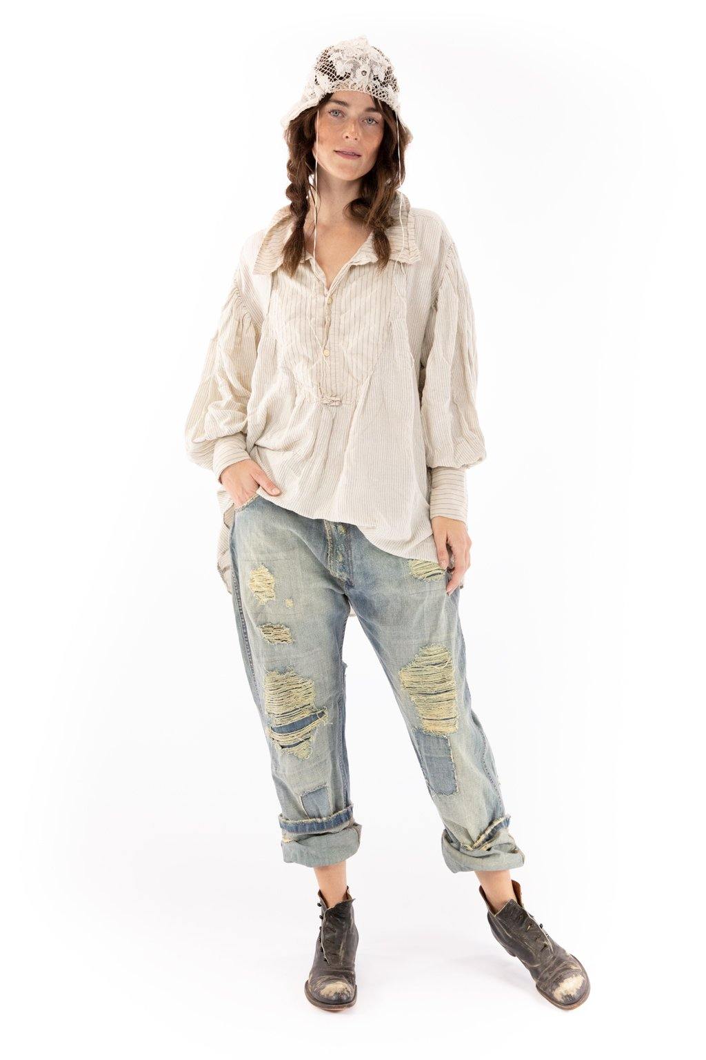 Woman in loose striped blouse, distressed jeans, lace hat, black boots on white background